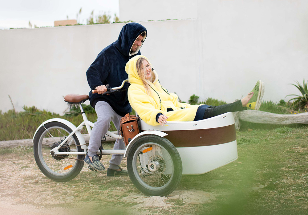 A couple wearing blanket hoodies on bikes