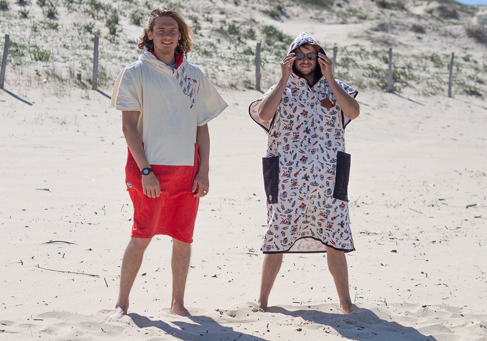 Two men having fun on the beach with ponchos